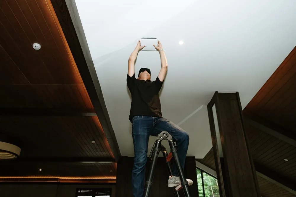 Technician mounting an indoor CCTV camera on the ceiling