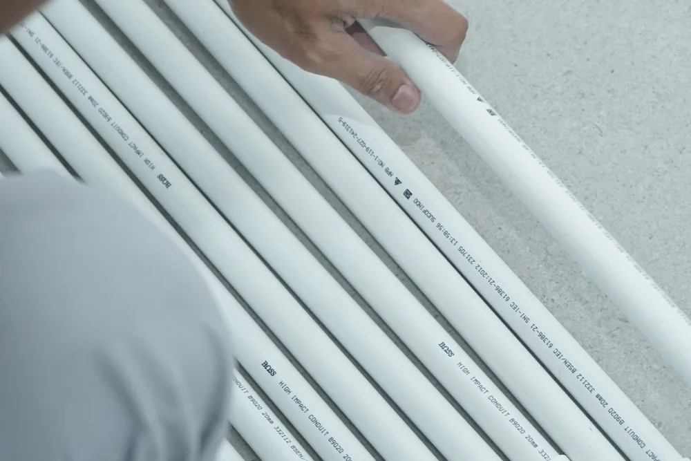 Technician holding BOSS high-impact PVC conduit pipes